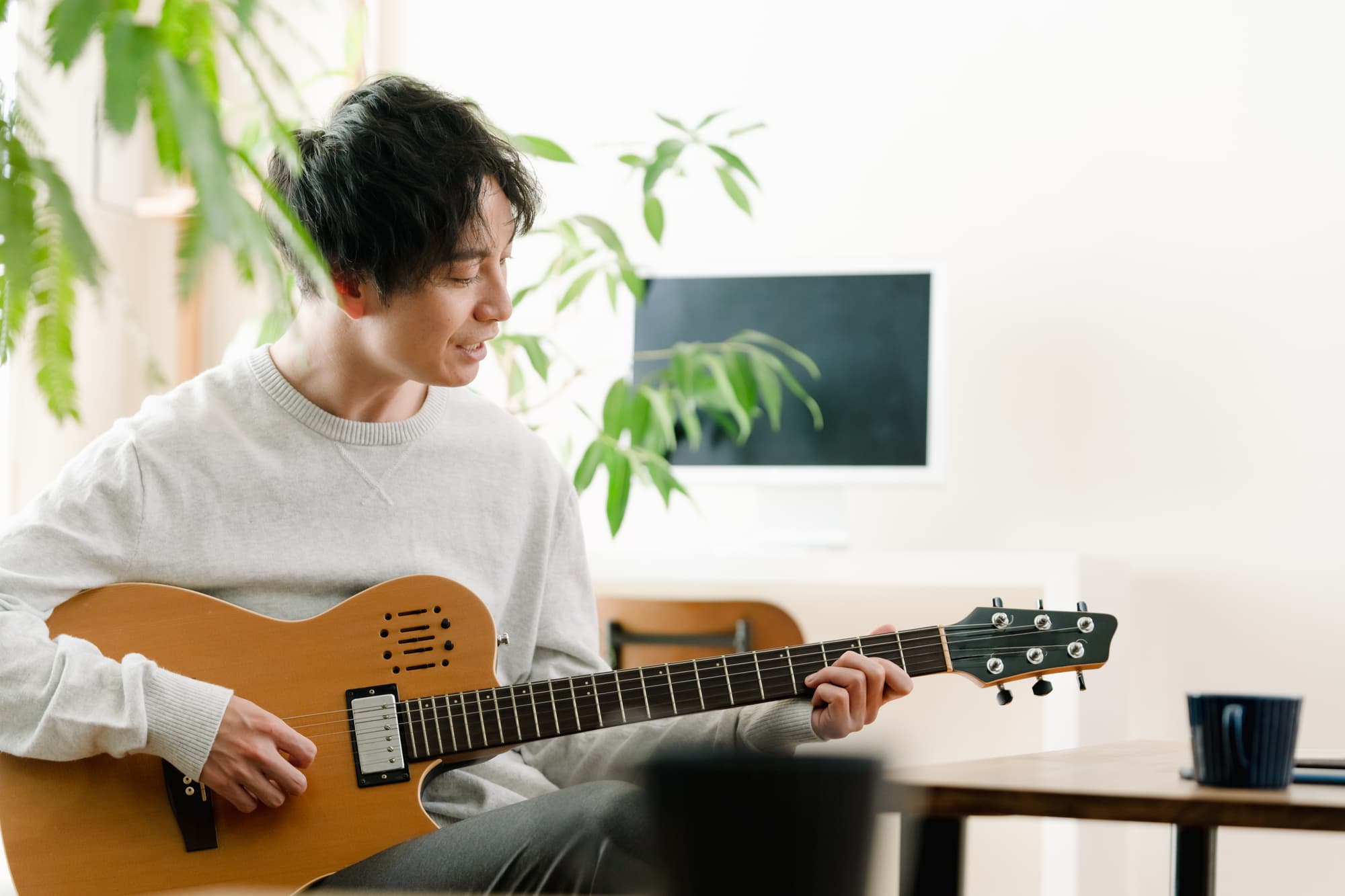 部屋でギターを弾く男性