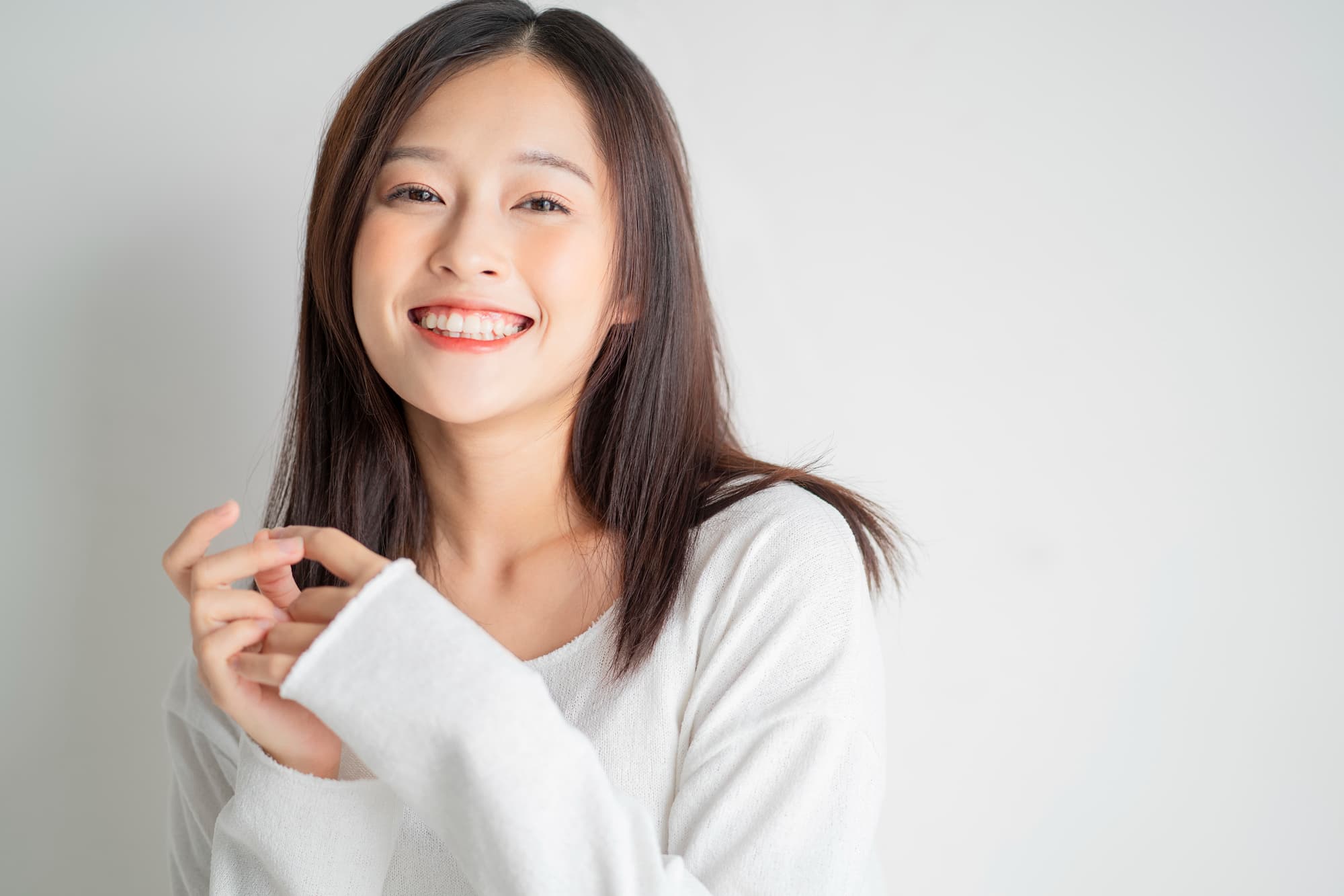 ホワイトニングをした白い歯に満足して微笑む女性