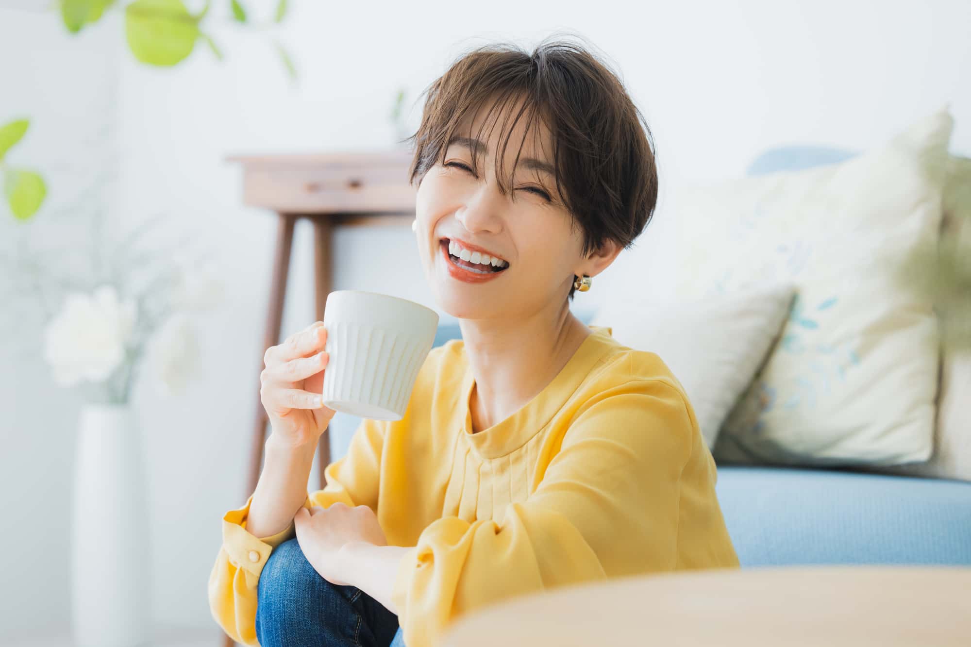 矯正で整った歯並びの女性が笑顔で飲み物を飲んでいるイメージ