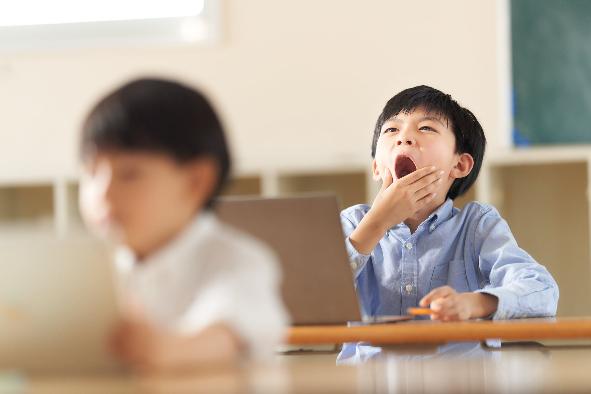 寝不足で授業中に欠伸をする子ども