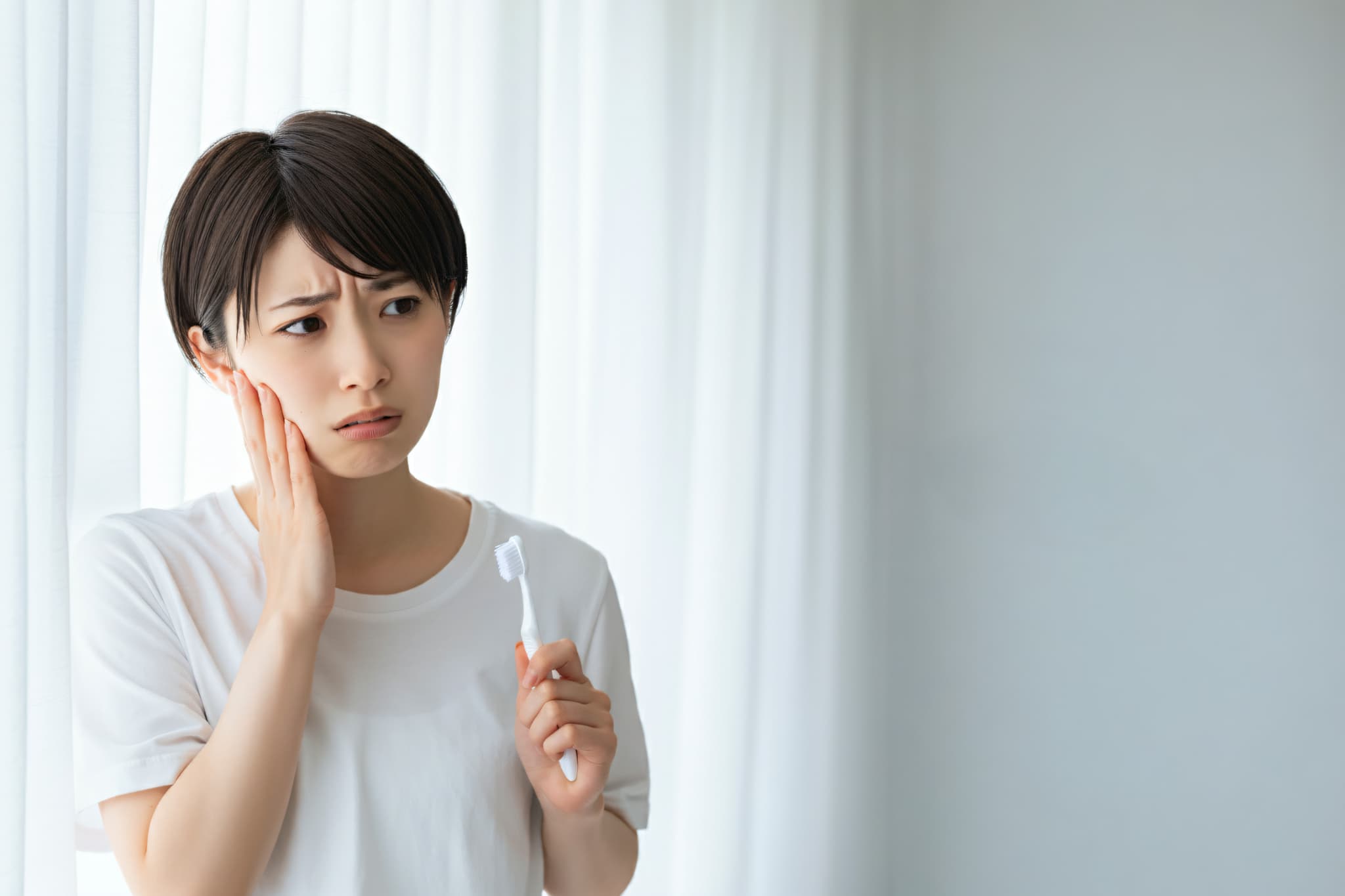 親知らずが生えてきて痛みを感じる女性