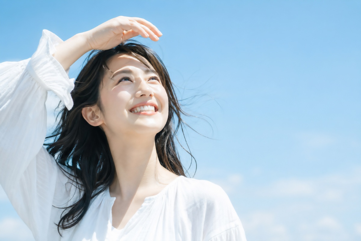 空を見上げて微笑む八重歯を矯正した女性